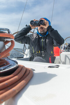 Sailor navigating Norwegian fiords with binoculars