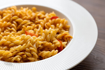 Close-Up of Italian Pasta with Tomatoes and Peppers on a White Plate