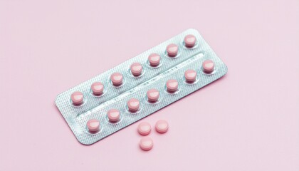 Pink medical contraceptive pills in blister on pastel pink background. 
