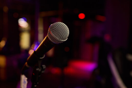 Performance setup with lighting and equipment, Closeup of microphone with vibrant stage illumination, Microphone prepared for performance amidst lively concert environment