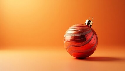 A single shiny red christmas ornament with swirling patterns on an orange background