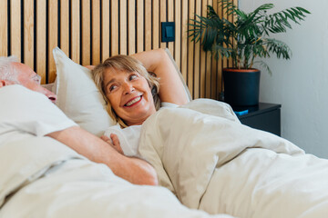 Happy senior couple relaxing in bed, enjoying morning conversation and intimacy, sharing a warm moment of love, connection, and enjoying retired life together