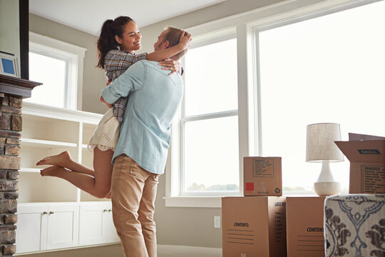 Excited, moving and couple hug in new home for bonding in property, apartment and house. Spin, marriage and man with woman embrace with purchase, real estate investment or mortgage for relocation - Powered by Adobe