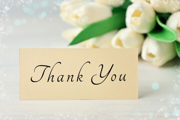 Thank You card and flowers on white wooden table, closeup