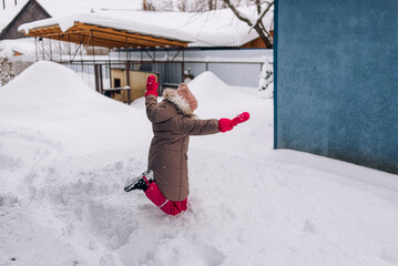 Child enjoying winter playtime in a snowy backyard