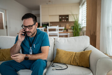 Male nurse receiving stressful phone call at home