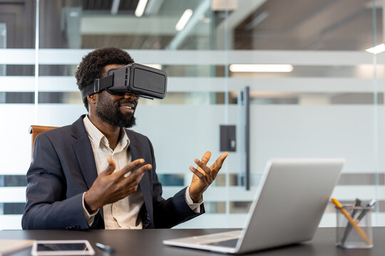 African american businessman wearing a virtual reality headset and gesturing while interacting with a digital world during a technology meeting in a modern office environment