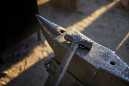 A detailed view of a blacksmith&rsquo;s hammer resting on an anvil