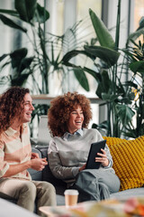Diverse friends laughing enjoying content on tablet