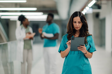 Medical professional using digital tablet in hospital corridor