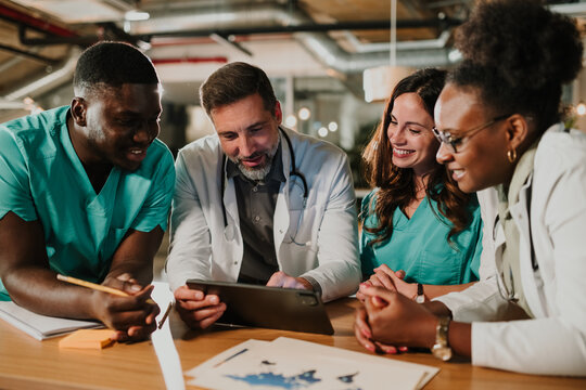 Medical team collaborating and discussing health data using tablet - Powered by Adobe