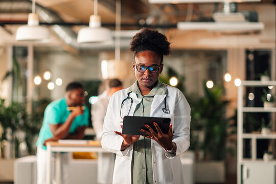 Black doctor using digital tablet in clinic