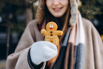 Woman holding gingerbread cookie on winter day