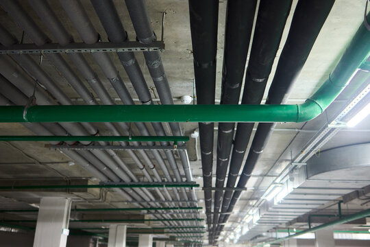 Subterranean parking details, Basement parking area equipped with lighting and plumbing, Underground vehicle shelter featuring electrical wiring and ventilation systems