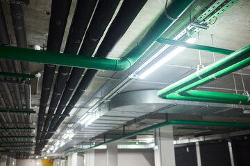 Subterranean parking details, Basement parking area equipped with lighting and plumbing, Underground vehicle shelter featuring electrical wiring and ventilation systems