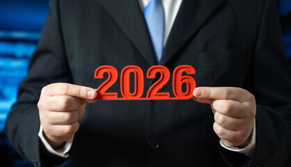 A businessman holds the year 2026 in his hands. New Year in business and commerce. Strategic planning and future opportunities. Corporate forecasting, growth expectations and annual economic outlook