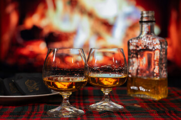 Deux coupes d'alcool fort et chocolats fins devant un feu de foyer, soir, horizontal