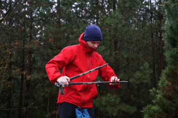 A young hiker sets up trekking poles for walking in the forest. The concept of active travel and trekking