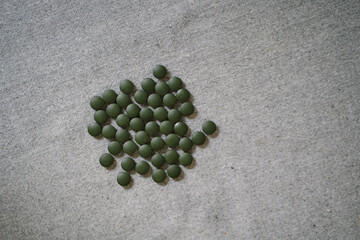 Green spirulina pills close up. Treatment of iron deficiency and anemia. Source of ferritin. Healthy supplement for vegetarians