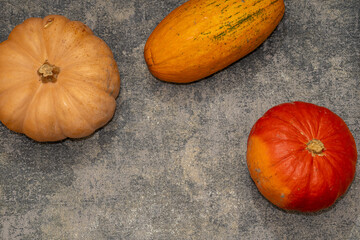 Top view of three assorted pumpkins and squash on a grey concrete or stone background. Modern autumn concept