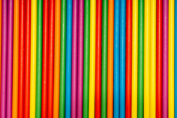 Full frame texture of arranged colorful wooden sticks. Vertical rainbow stripes background pattern