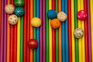 Abstract flat lay of scattered decorative wooden beads on a background of vertical rainbow colored sticks