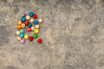 Top view of a pile of colorful wooden beads on a rustic grey stone background. Crafting materials for children