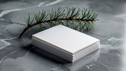 Obraz premium Stack of Blank Cards with Pine Branch on Marble Background