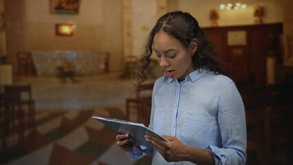 Woman holding clipboard, hand covering mouth while reading from papers in a church building with pews and altar in view; grief prayer.