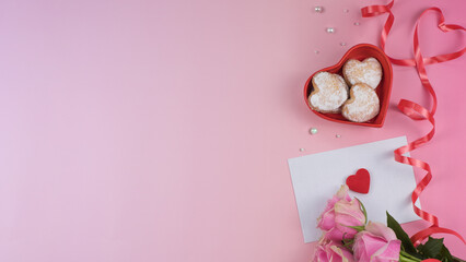 Romantic Valentine setup with heart-shaped cookies, envelope, and roses with copy space