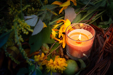 Warm glow enhances peaceful evening, Rustic scene illuminated by gentle amber flames atmosphere, Basket with candles and flowers creates calming seasonal setting