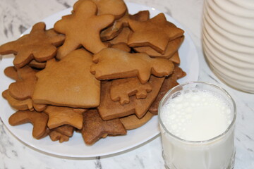 Cookies and milk on a table with a variety of shapes during a holiday gathering in a cozy kitchen setting