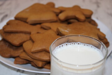 Delicious gingerbread cookies on a plate with a glass of milk on a table during a winter celebration