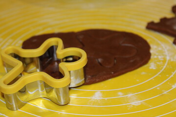 Making cookies with a star-shaped cutter and brown dough on a yellow rolling mat during a baking session
