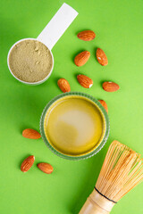 Matcha powder protein drink, vegan matcha tea protein whey shake cocktail, with almond.Healthy vegetarian superfood, trendy diet beverage, with protein powder in scoop, on white green background