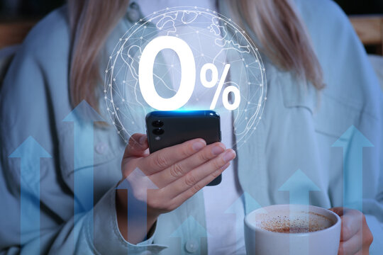 Woman using mobile phone indoors, closeup. 0 percent sign and globe above device. Zero commission - Powered by Adobe