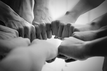 Group of people holding their fists together, closeup. Black-and-white toning
