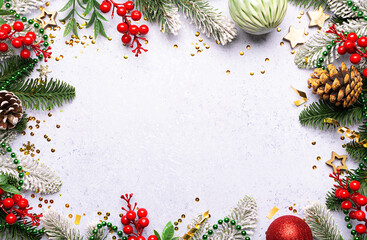 Festive Christmas and New Year frame made with fir tree branches, pine cones and golden decorations on light marble background with copy space for your design.