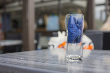Empty Glass with Folded Blue Napkin on Outdoor Cafe Table in Summer City Terrace. Finnish summer lunch.