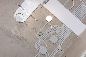 Installation of electrical wiring on the ceiling. The electrical wires in the protective corrugated cable tube in the repaired room.