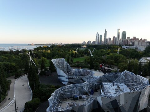 Aerial View of Maggie Daley Park Skating Ribbon and Chicago Skyline at Sunrise High-resolution aerial image showcasing the Maggie Daley Park Skating Ribbon surrounded by lush greenery, 