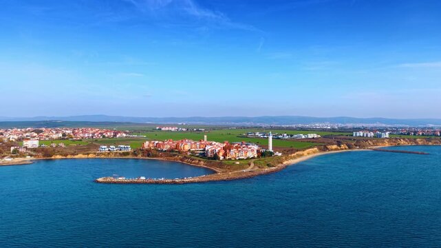 Scenery of the sunny coast of the Black Sea from the drone footage over the waterscape. Cozy residential area of Aheloy, Bulgaria with a lighthouse at the shore.