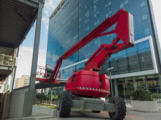 Red boom lift at construction site updating modern building