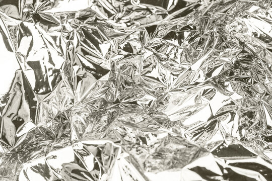 Crumpled shiny metallic silver foil surface creating an abstract background texture with reflective light and shadows. Color of 2026 year dancer in the white cloud