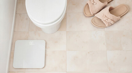 Wc with toilet bowl, scales, and slippers on beige tiled floor captures wellness scene. Wc setup includes simple toilet bowl, a set of scales for measuring weight, and cozy slippers.