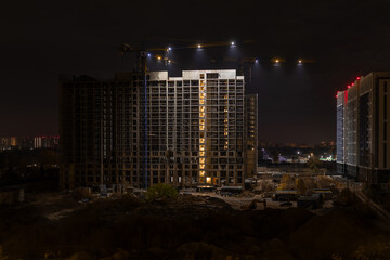 Nighttime View of High Rise Construction Site with Cranes and Building Frame