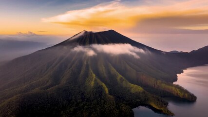 An aerial shot of a stunning mountain landscape, featuring a large, majestic volcano surrounded by clouds Stock Video - Powered by Adobe