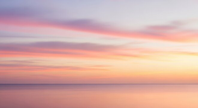 Soft pastel colors paint the sky at sunset over a serene ocean