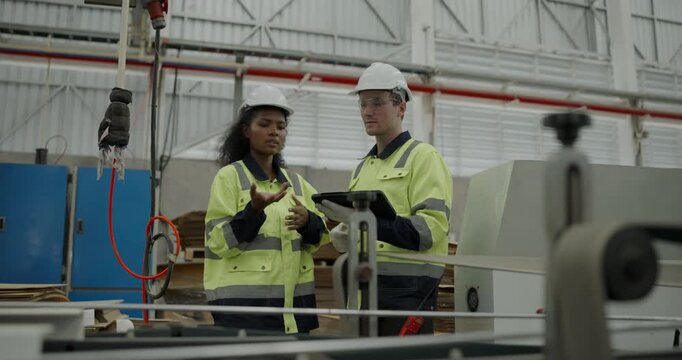 Industrial concept of 4k Resolution. Engineers are inspecting a cardboard cutting machine in the factory with strict attention to safety procedures.