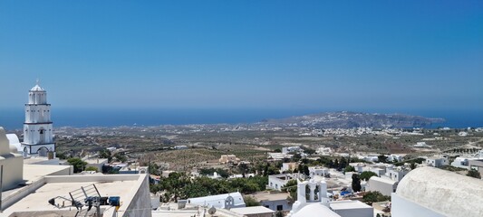 View of the coast and buildings from a high point in Santorini, Greece during a sunny day with clear blue sky